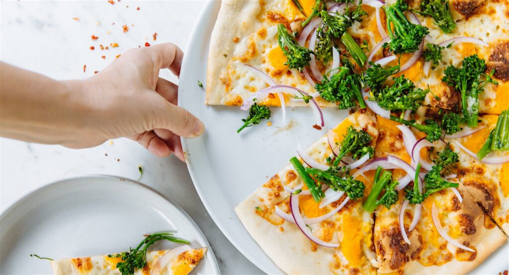Hand holding platter of wood-fired pizza at Birba.